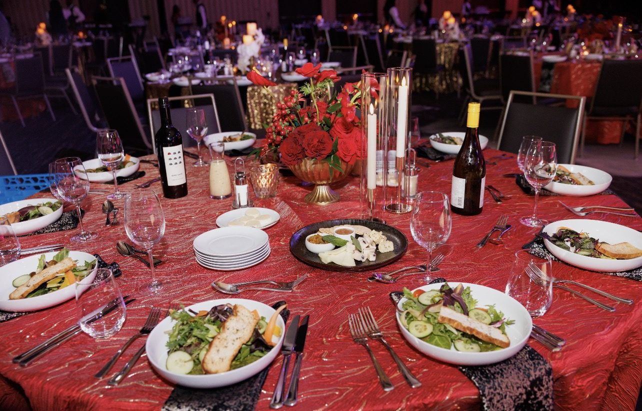 Dinner table with red linen, red rose centerpiece and taper candles